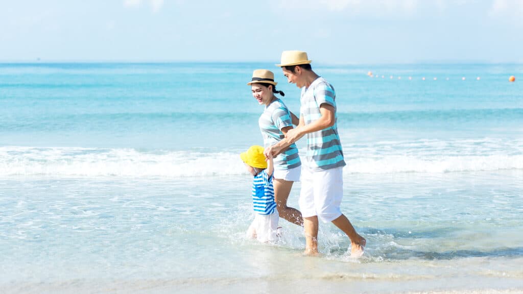 Asian happy family have fun water sea on the beach. Parent and daughter traveling backpack for travel in vacations for leisure and destination. Family tourism travel in summer and holiday. Travel and Family Concept